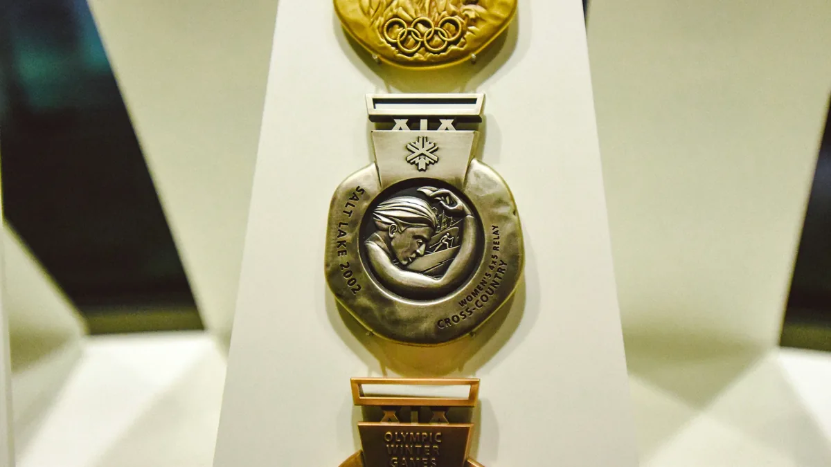Three Olympic medals displayed on a white stand, with the top medal being gold, the middle medal being silver, and the bottom medal being br