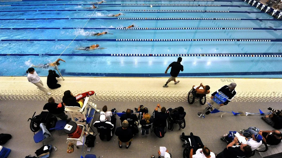 A swimming pool with swimmers in the water and spectators on the deck.